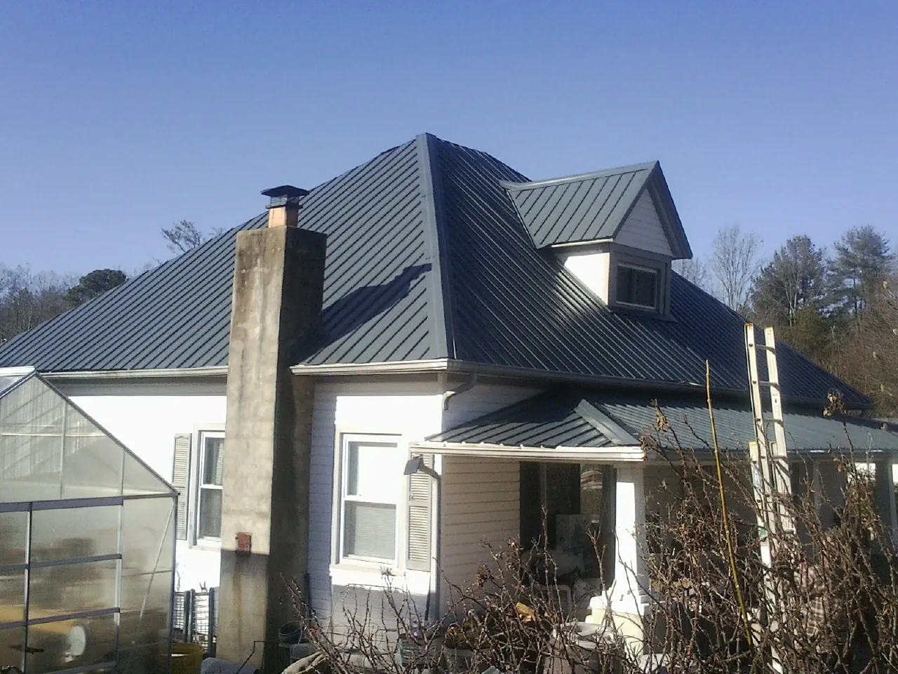 Dark blue standing seam metal roof on a white farmhouse with dormer — Slate & Tile Roof Repair by Roofing Brothers in Quincy