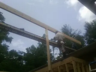 Carpenter setting a ridge beam over a new addition frame — Ice Dam Removal by Roofing Brothers in Quincy
